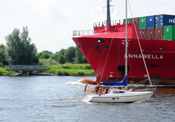 Schiffsverkehr auf dem NOK: Ein Containerschiff und ein Segelboot begegnen sich.