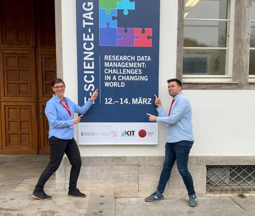 Tabea and Jonatan posing in front of the E-Science-Tage poster