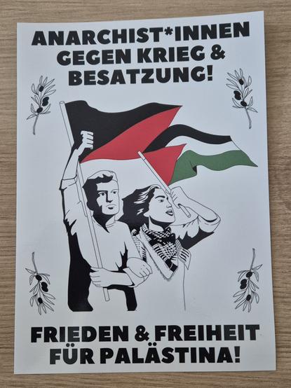 Auf dem Bild ist ein Sticker mit politischen Abfindungen zu sehen, welcher auf einem.Tisch liegt:

Im uberen Drittel des Stickers steht:
Anarchist*innen gegen Krieg und Besatzung!

In der Mitte des Bildes des Stickers:

Dort sind 2 Personen abgebildet, ein Mann und eine Frau. Der Mann schwenkt eine schwarz-rote Fahne.
Die Frau schwenkt die palästinensische Fahne und trägt eine Kufiya.
Außerdem sind an den Eckenjeweils an Olivenbaumzweigen umrandet. Es sind insgesamt 4 Olivenzweige.

Im unteren Drittel steht:

Freiheit und Frieden für Palästina