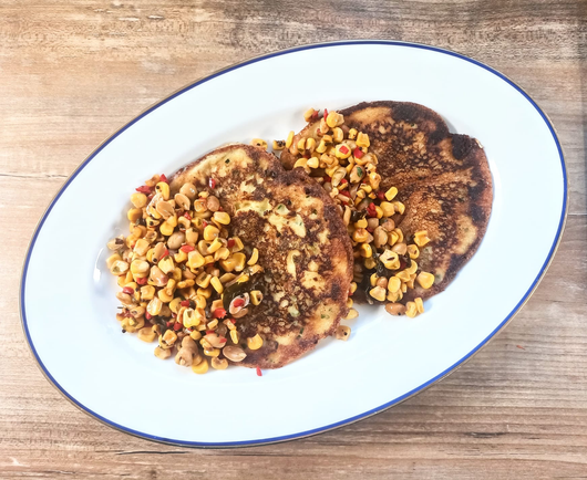 Zwei Pfannkuchen auf einer Servierplatte mit Maissalat mit Chili + Erdnüssen.