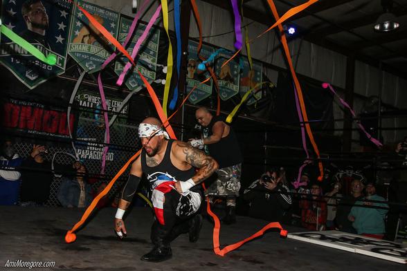 Homicide kneels while celebratory streamers are thrown in the ring