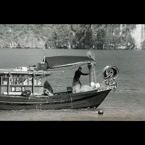 B&W phtography of a fisherman in his boat, Halong bay in Vietnam