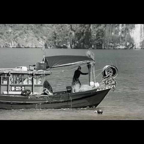 B&W phtography of a fisherman in his boat, Halong bay in Vietnam