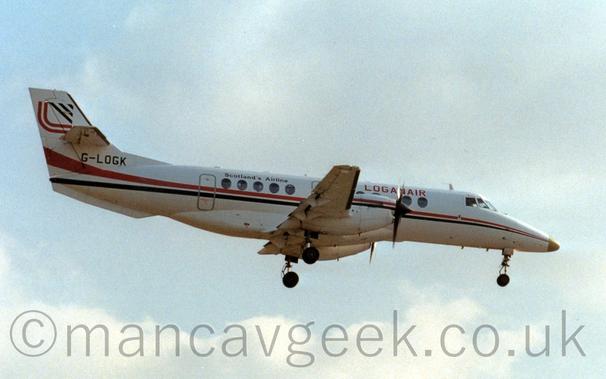 Side view of a white, twin propellor-engined airliner flying from left to right at a low altitude, with undercarriage lowered and flaps extended from the rear of the wings, suggesting it is about to land.
There is a thin red and black stripe running along the body and engine cowlings, with red "LoganAir" titles on the upper forward fuselage, and black "Scotland's Airline" titles on the upper rear.
The registration "G-LOGK" is on the lower part of the tail in black, while the upper tail has a heavily stylised "LA" logo in red and black.
Cloudy grey sky fills the rest of the frame.