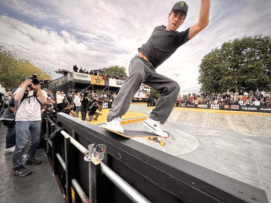 Tom Scharr performs a frontside tail stall on a bowl's extension on a mostly cloudy day.