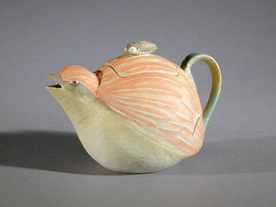 “Description teapot in the shape of a sparrow in orange and yellow, of grey clay with enamel or slip decoration; lid has a cicada finial Colour: brown/yellow”