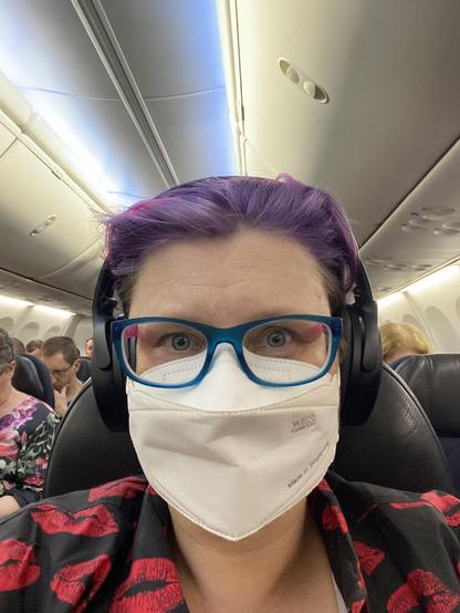 On the plane on the way back from Sydney wearing a silly Hawaiian shirt covered in kisses, a white mask and a tired but happy expression.