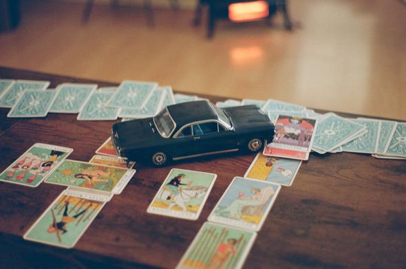 A Celtic cross tarot spread is laid across a wooden coffee table. A 1:18th scale dark blue 1963 Corvair Monza Coupe model faces NE, tellingly towards ‘The Lovers’ card in the outcome position.