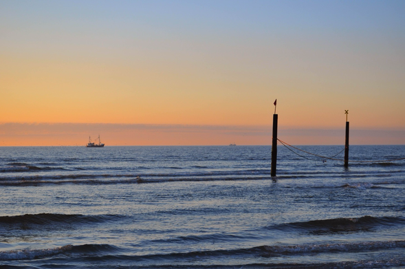 Strand von Norderney am Horizont ein Schiff vor dem Abendhimmel