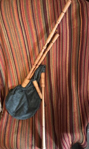 A nicely made set of bagpipes in towns wood with a black leather bag. The two drones are in a common stock, and the bag is quite round.