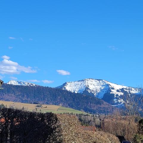Blick zu verschneiten Bergen, blauer Himmel mit kleinen Wolken