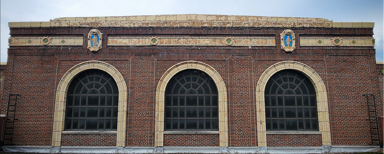 Color image of three arched windows on Rankin Elementary School, c. 1926, Akron, Summit County, Ohio, USA, currently being razed. Image shows three large arched windows, arches made of terra cotta, below an entablature also made from terra cotta, holding the school's name centered, with fanciful bracketing of historical figures. The building is red brick.