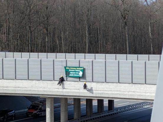 Menschen Seilen sich von wildbrücke mit Banner ab