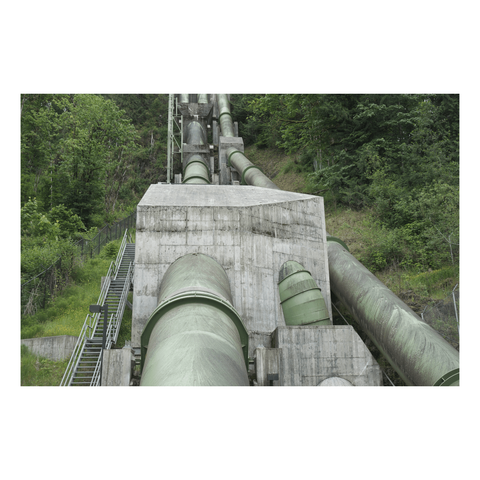 enormous pipes coming dow a steep slope in a clearing in the woods