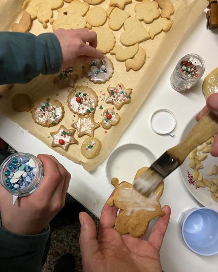 Weihnachtsplätzchen werden mit bunten Streußeln belegt