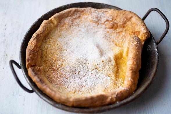 A pan with a freshly baked Dutch baby, dusted with powdered sugar.