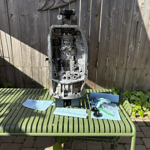 On top of the green metal patio table in my backyard, the ZF 5HP19 five-speed automatic transmission from my 2003 BMW 530i stands upright, its bell housing end supported a few inches above the table by two stacks of black rubber blocks. The oil pan and valve body are removed, making it possible to see that all of the clutch packs and gear sets have been installed into the case.