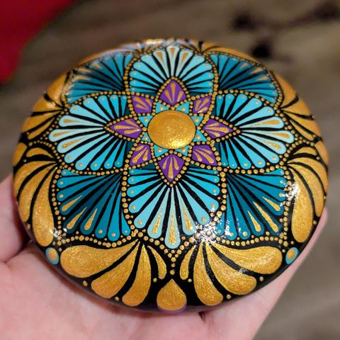 The same stone, but angled a bit, to show more of the outer edge. Around the main flower design are large teardrop blobs of gold accenting the design, forming a decadent-looking decorative border.