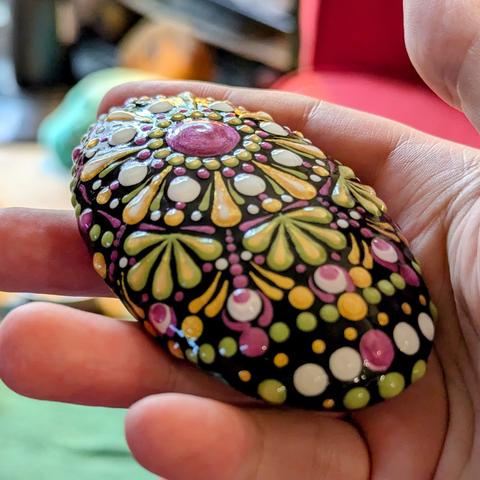 The stone held on an angle to the light, showing off the raised glossed bumps complementing the dots painted on its surface.