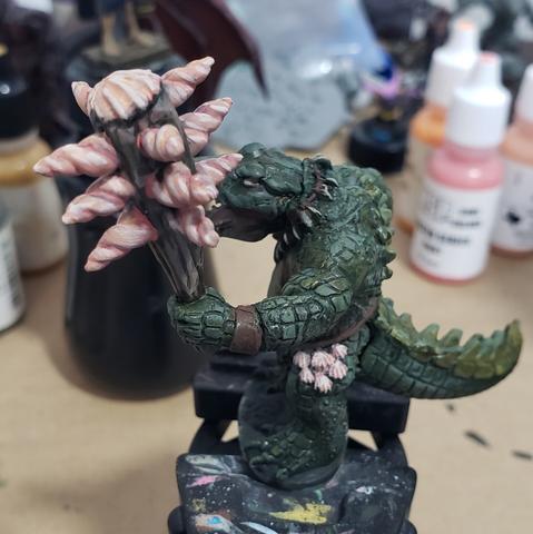 Gator Man with club embedded pointy twisty seashells painted in pale pastel pinks.