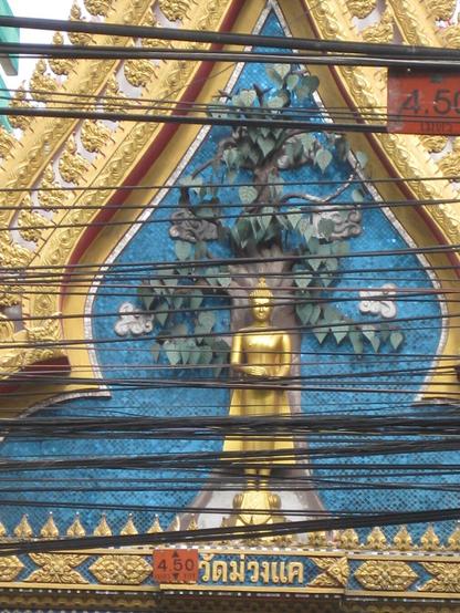 A colourful relief of a buddha obscured by electrical cables
