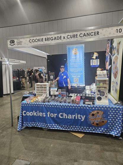 Picture of booth setup with banners saying Cookies for Charity. Funds raised support Cure Cancer