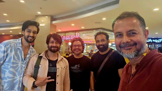Sourabh Raaj Jain (left) and Mukesh Kumar Singh (right) huddle with friends for a photo inside a retail complex. Sourabh wears a loose-fitting white and pale-blue summer shirt, while Mukesh sir wears a deep red polo shirt. The image was posted on Instagram by Mukesh sir on Feb. 23, 2025.