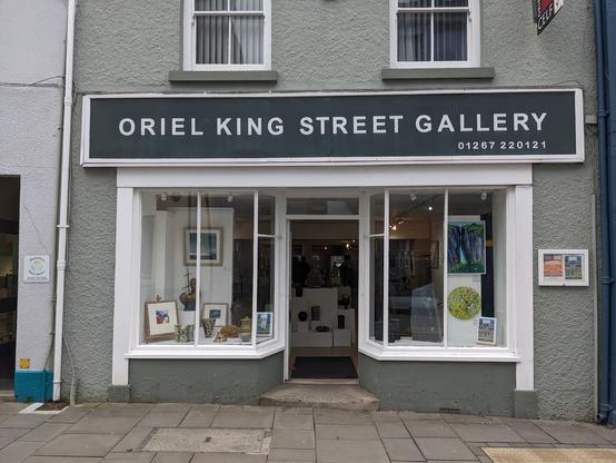 Double windowed shop front in a grey two storey terrace. Sign above says Oriel King Street Gallery.