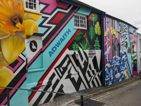 Vibrant wall painting on a side alleyway. Daffodils, abstract shapes, birds and waves.