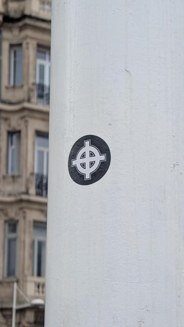 Photo d'un sticker croix celtique sur un poteau blanc.