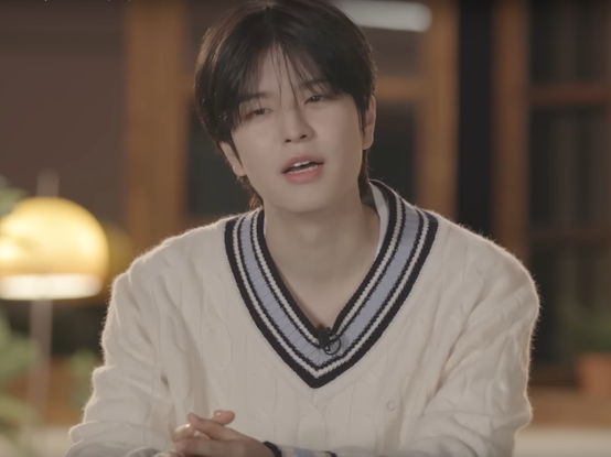 Seungmin sitting in front of a warm-toned living room at night
