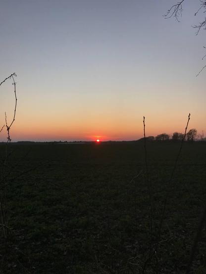 beautiful orange and rd and light blue sunset with strong contrast to the dark black ground