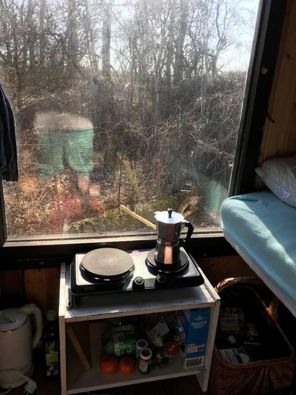 a little kitchen inside a bauwagon
a coffeepot
a little stove
looks cute and trashy in a good way
you can see some of my bed too
and a big window showing nature outside