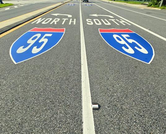 Colorful interstate highway markings for I-95 on the pavement near an intersection with on-ramps.
