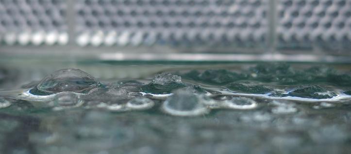 Melting hexagonal hailstones, whose crystallization nuclei are snowflakes, lie on a glass plate. A reflector is in the background.