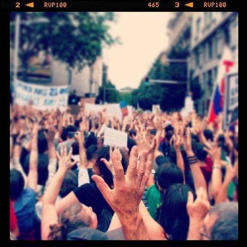 Tones of hands raised in a demonstation in the streets of Barcelona, near Catalunya Square. One of the hands is focused in the center of the image.