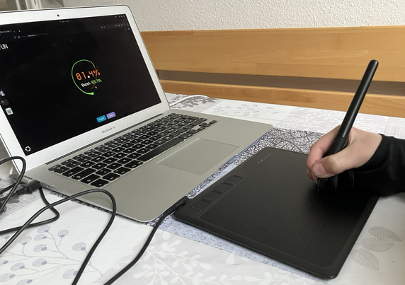 The graphics tablet is connected to a MacBook from 2011. The MacBook is running Ubuntu 24.04. In the browser you can see a website where you can draw circles.