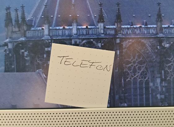 Zettel mit der Aufschrift "Telefon" klemmt am Rand eines PC-Monitors.