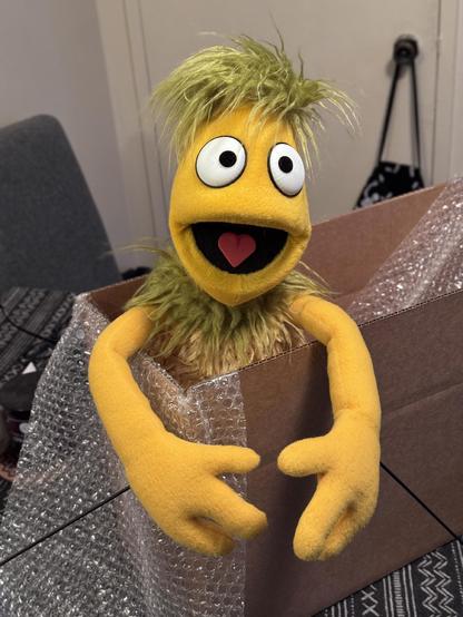 A yellow conehead puppet being boxed for shipping