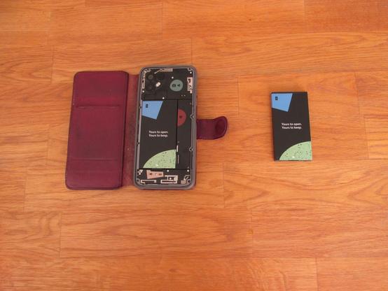 (The battery has been swapped.) The phone with the removed back cover looks the same (except it's equipped with a fresh battery now). To the right lies the old battery.