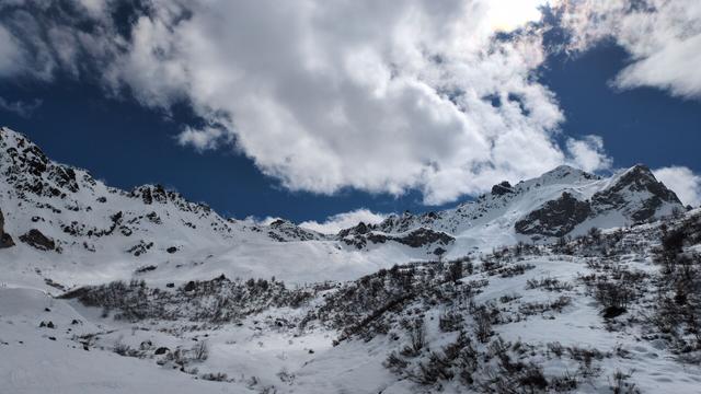 White clouds on a dark blue sky and white snow covered mountains.