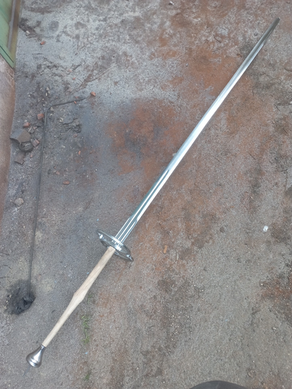 A nearly-finished schlachtschwert - a two-handed late medieval battle sword - rests on the ground.
