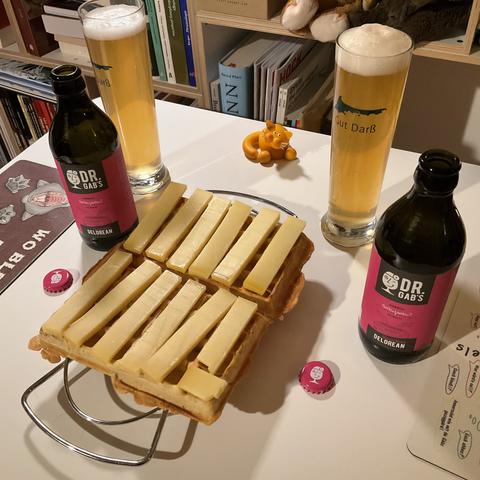 zwei eingeschänkte Gläser, zwei Flasche Dr. Gab's DeLorean, belgische Waffel mit Käse