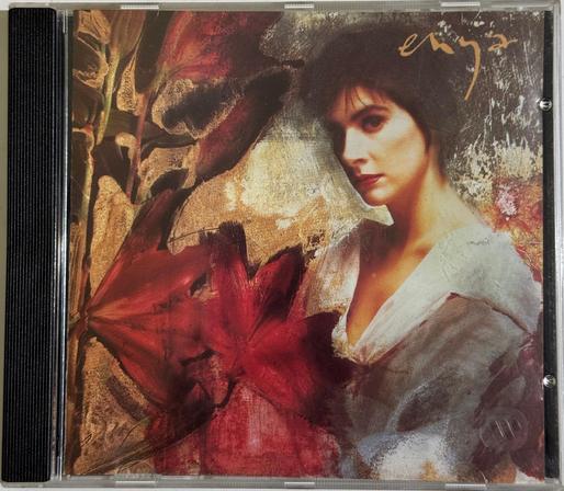 The CD cover for Watermark. Oil-painting style illustration of a women (Enya) with dark hair near some dark red flowers or leaves (it's not clear which).