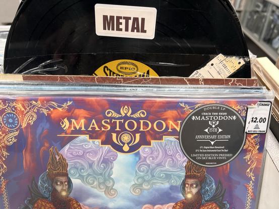 Photo of the top of an LP for Mastodon (the band) Crack the Skye, 15th anniversary edition. It is in a bin of records, labeled “metal” at the top.