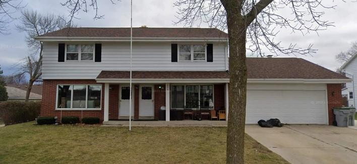 Street view of the same place from December 2022. Same white siding upstairs and brick downstairs. Same white doors.