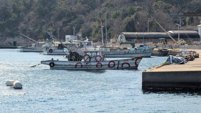 A small fishing boat moored at its pier. Its side is painted with big red circles and more.