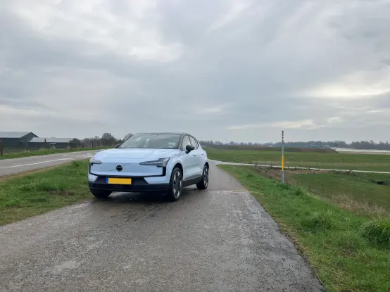 A cloud blue Volvo EX30 parked on a dike road; panoramic front view.