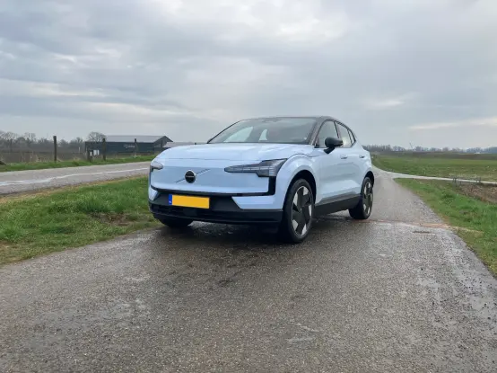 A cloud blue Volvo EX30 parked on a dike road; zoomed in front view.