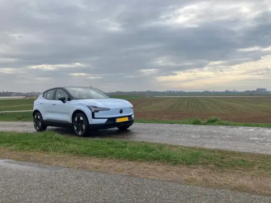A cloud blue Volvo EX30 parked on a dike road; panoramic 45 degree front view.